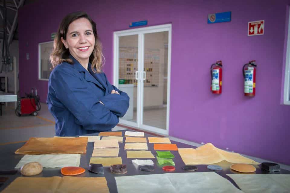 Sandra Ortiz stands in kitchen behind table filled with vaiations of her new plastic