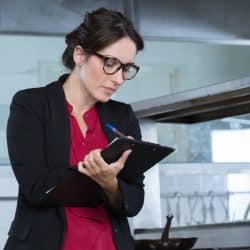 woman restaurant manager with clipboard inspecting kitchen