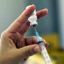 Nurse's hand holding a syringe giving a vaccination to a patient