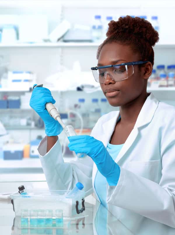 African-american scientist or graduate student in lab coat and protective wear works in modern laboratory