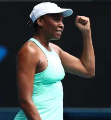 Venus Williams holding her fist up in victory while holding a tennis racket