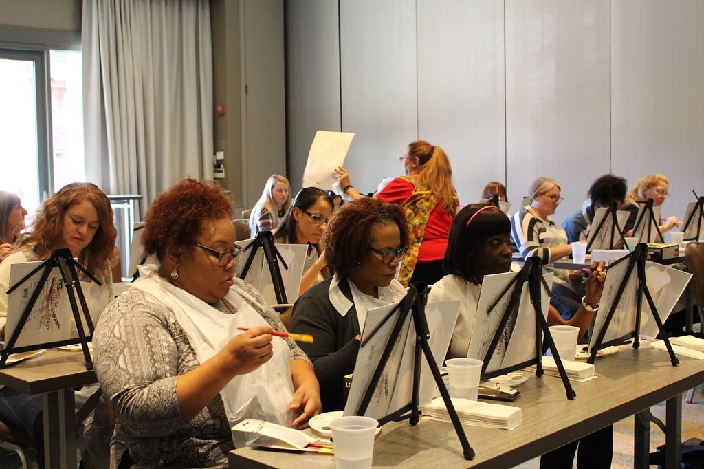 30 women sitting painting a picture
